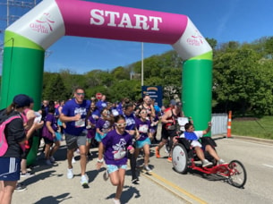 A GOTR 5K participant in an adaptive wheelchair kicks off the event under the start arch.